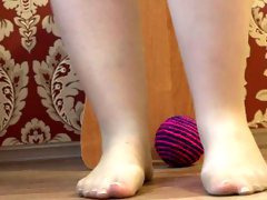 Beautiful plump legs play with a ball. A nice pedicure, thin nylon and high